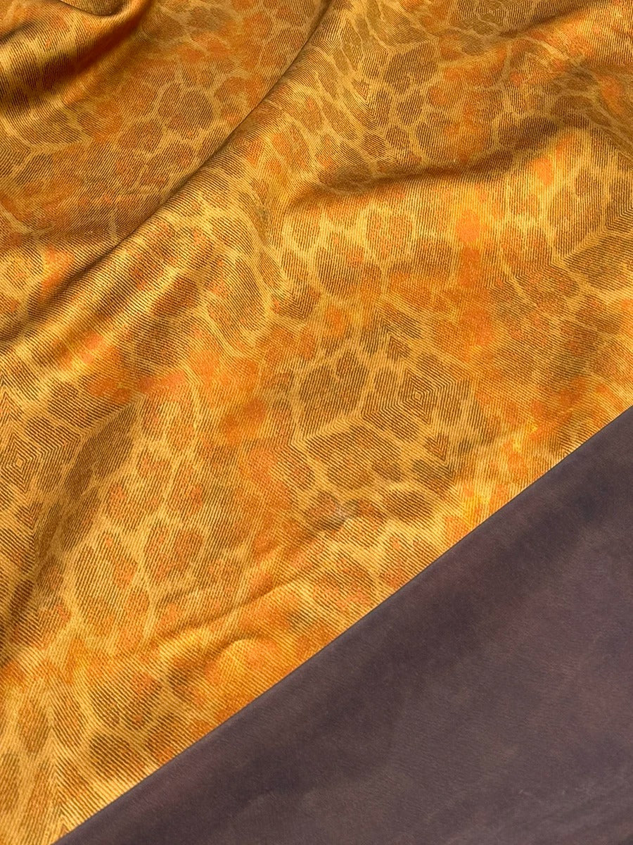 a close-up view of a fabric with a distinctive leopard print pattern. The fabric appears to be a blend of two colors, with the top part being a darker shade of brown and the bottom part being a lighter shade of orange. The pattern on the fabric is intricate and detailed, with the leopard's spots and markings clearly visible.