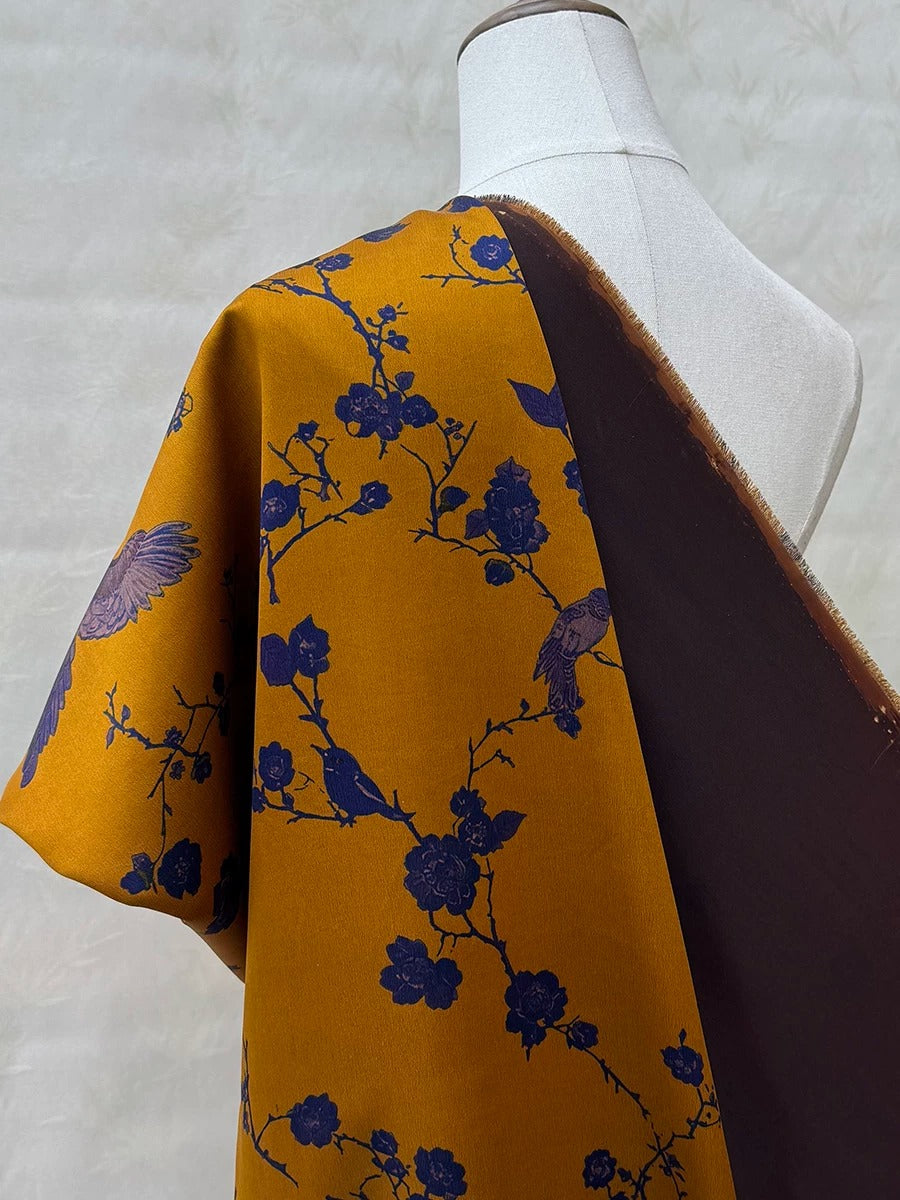 a mannequin wearing a yellow and blue floral print dress with a dark brown shawl draped over it.