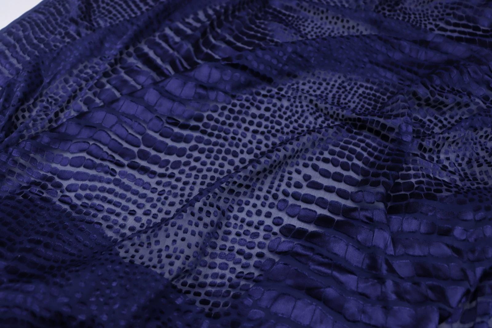 a close-up view of a fabric with a distinctive pattern resembling scales or scales, giving it a textured and visually interesting appearance.