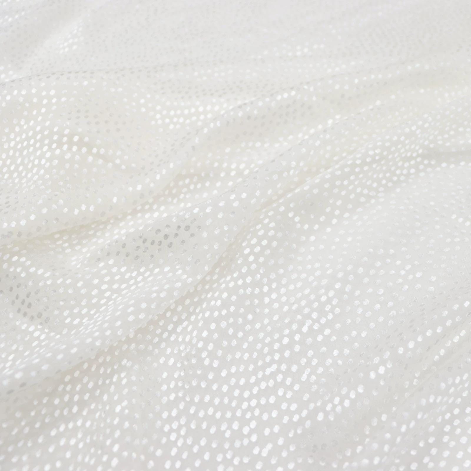 a close-up view of a white fabric with small white dots or sequins, creating a textured and shiny appearance.