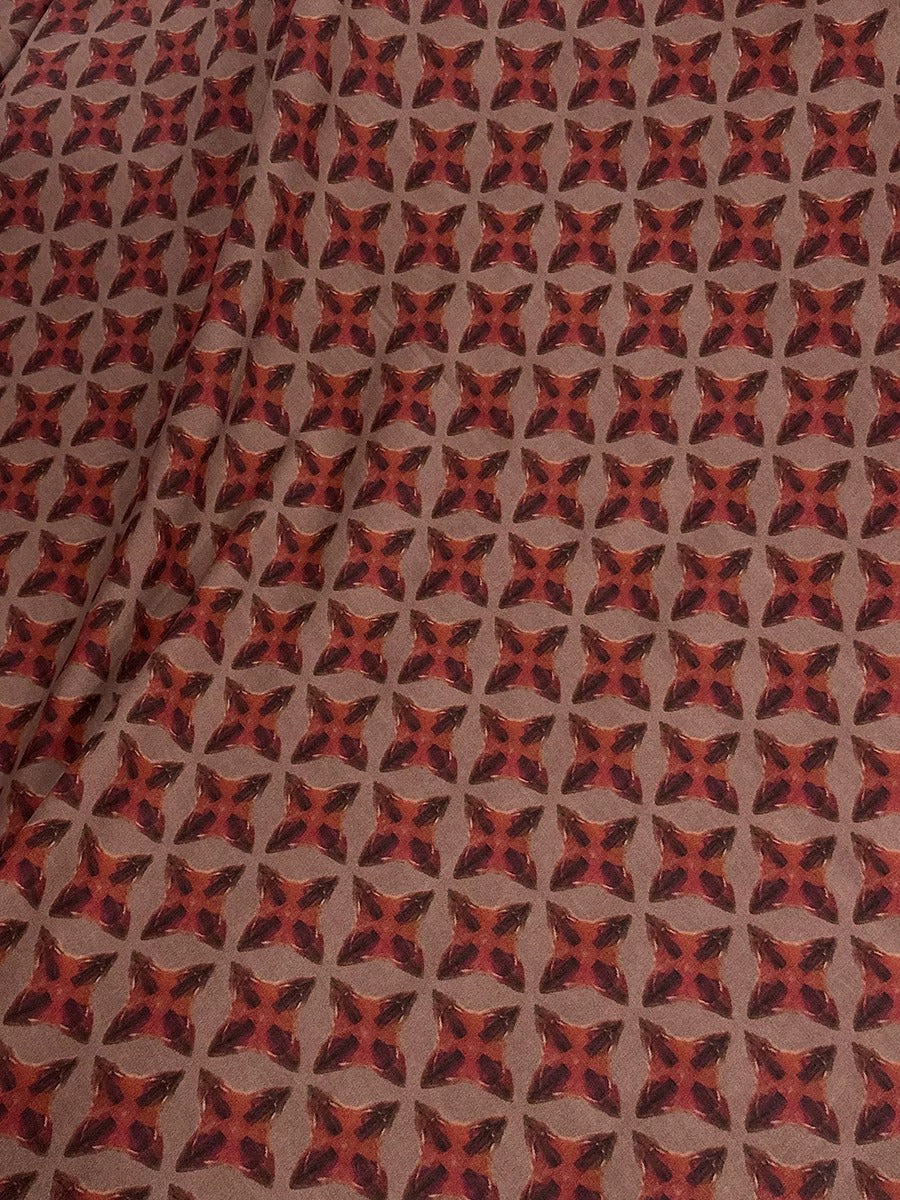 a fabric with a repeating pattern of red and brown geometric shapes, creating a visually striking and symmetrical design.