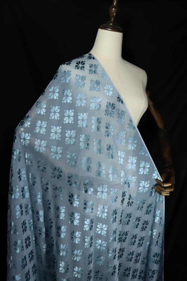 A mannequin wearing a light blue fabric with a floral pattern.