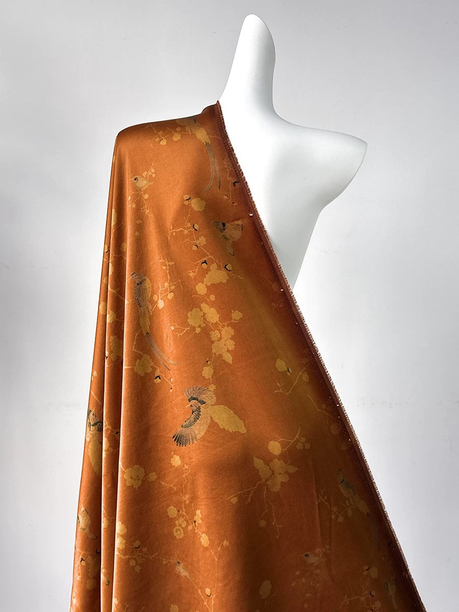 A mannequin wearing a long, orange-colored fabric with a floral pattern.