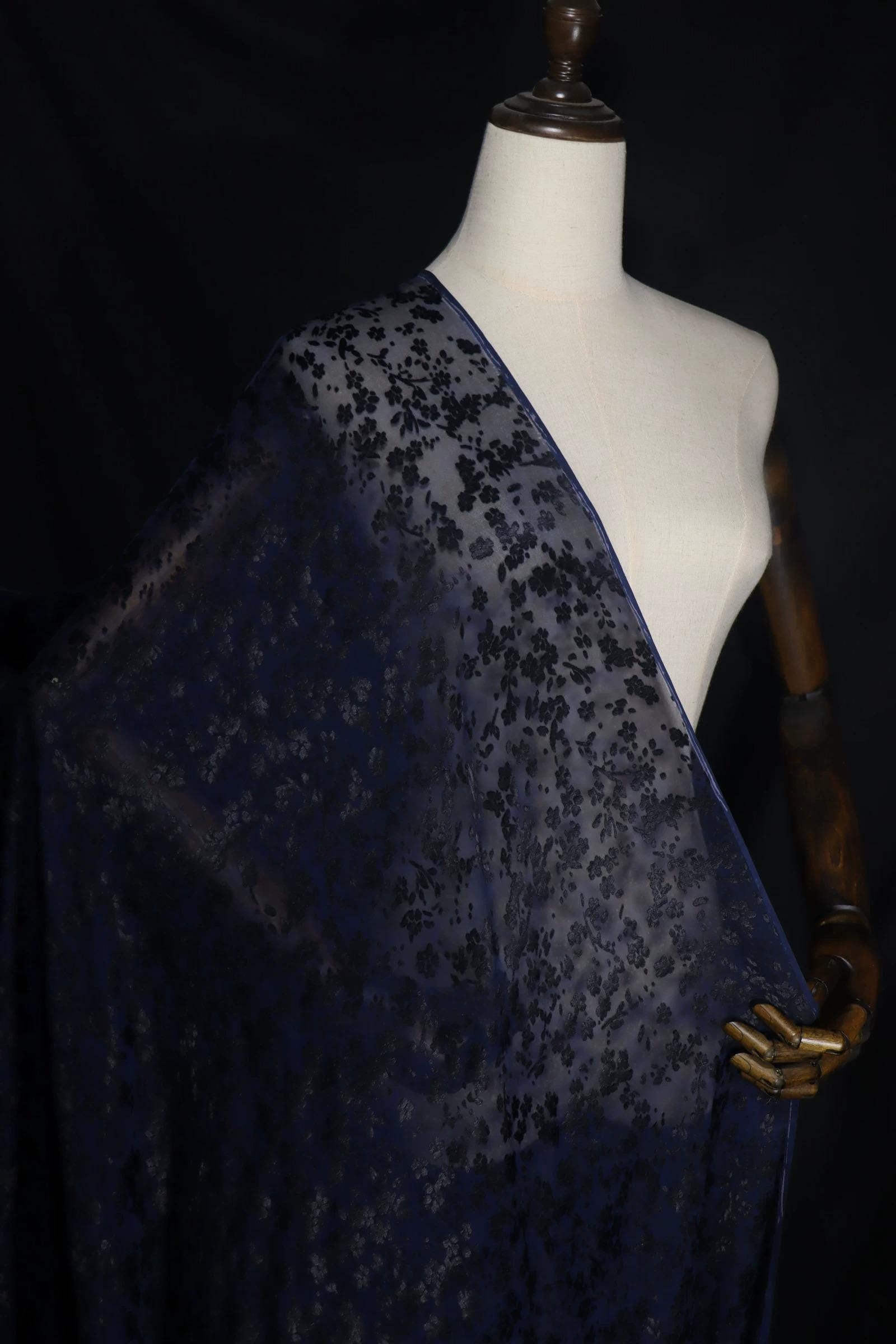 A mannequin wearing a blue and black floral fabric draped over its body.