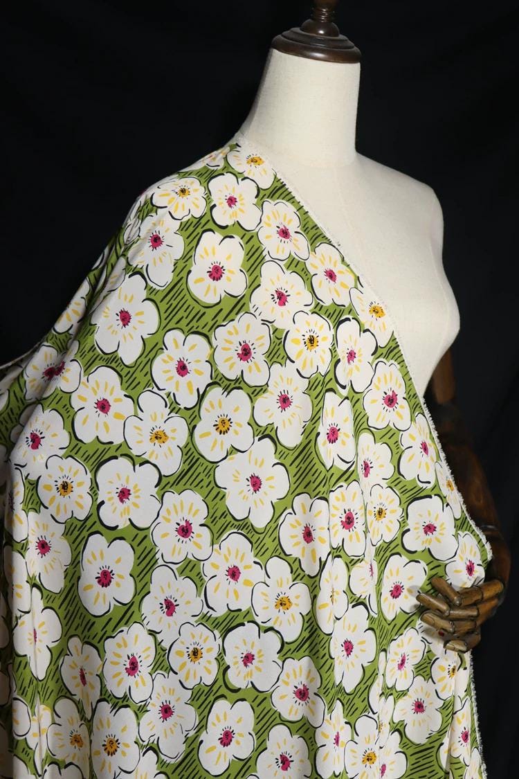 A mannequin wearing a green and white floral print dress with a white and yellow floral pattern.