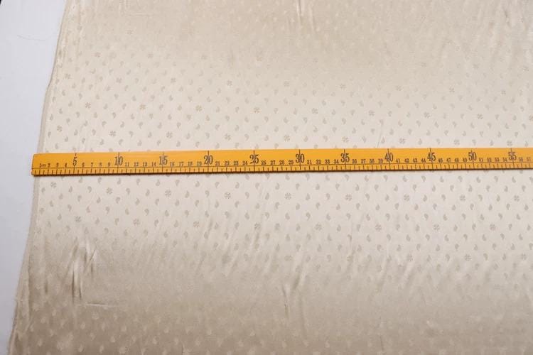 A yellow measuring tape is placed on a fabric with a dotted pattern.