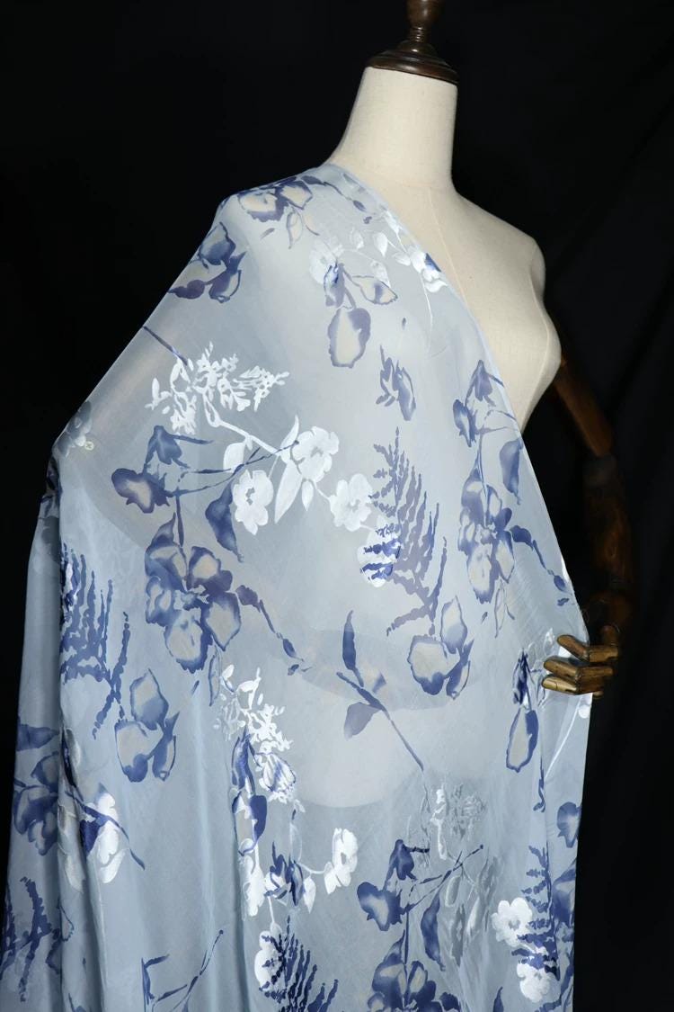 A mannequin wearing a light blue and white floral print fabric draped over its body.