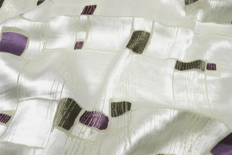 a close-up view of a fabric with a geometric pattern of purple and gray squares.