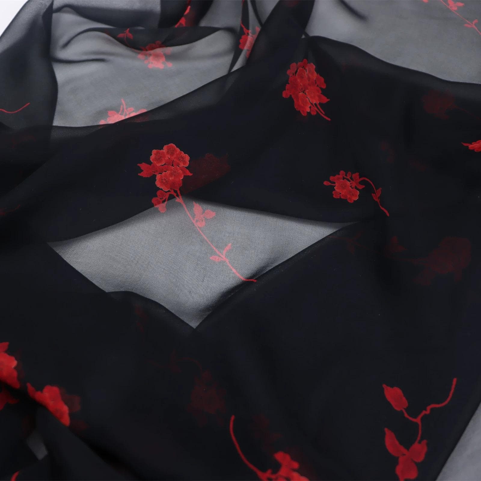 a close-up view of a black fabric with red floral embroidered patterns.