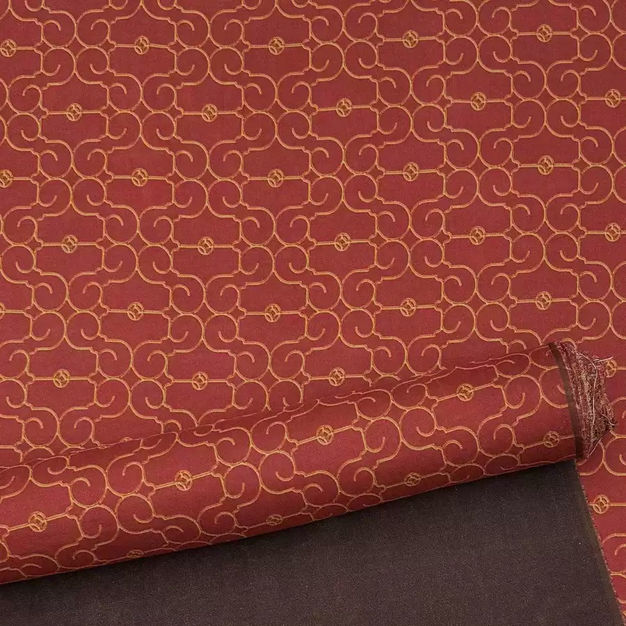 a red and gold patterned fabric with a repeating design of swirls and circles.