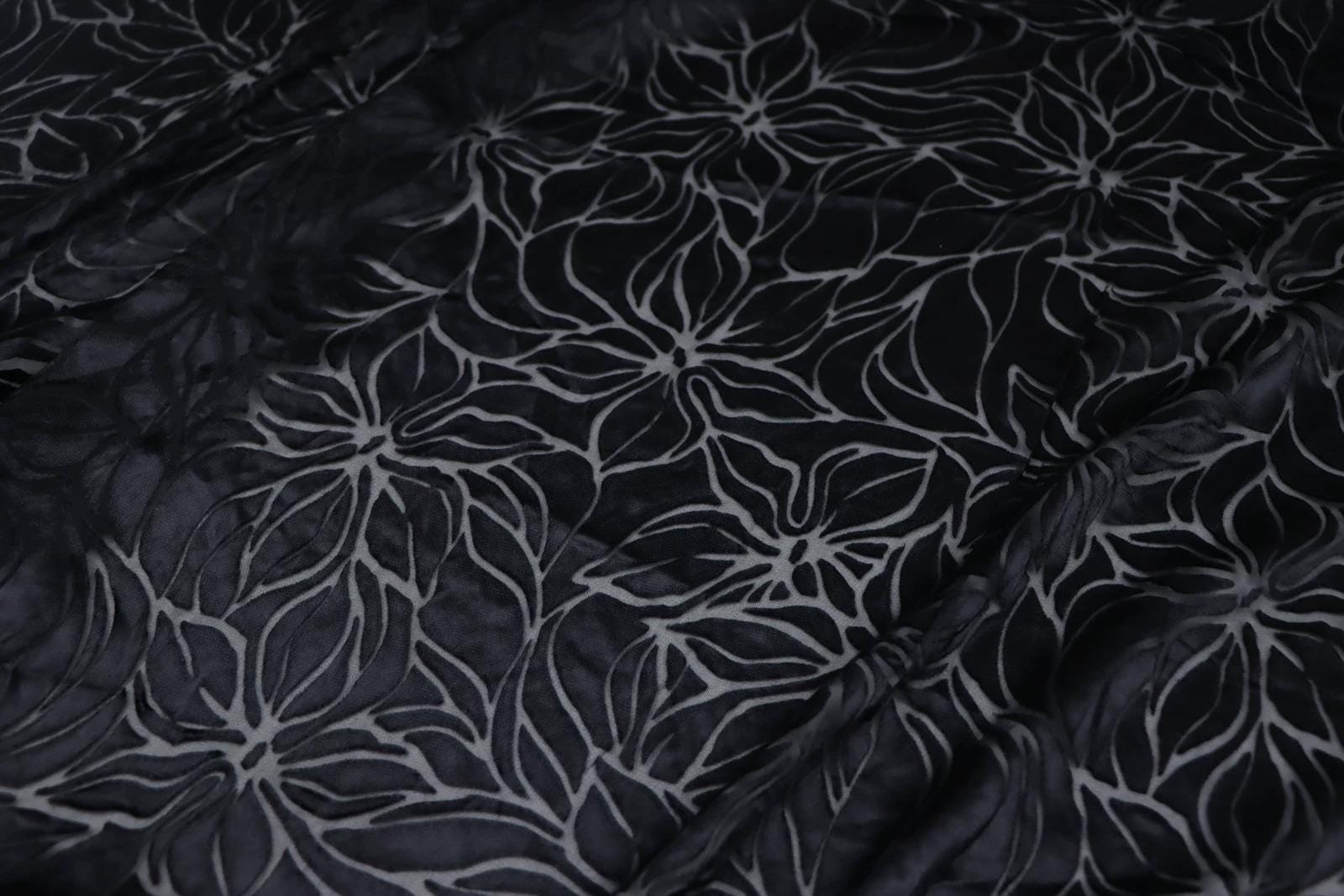 a close-up view of a fabric with a repeating floral pattern in black and white.