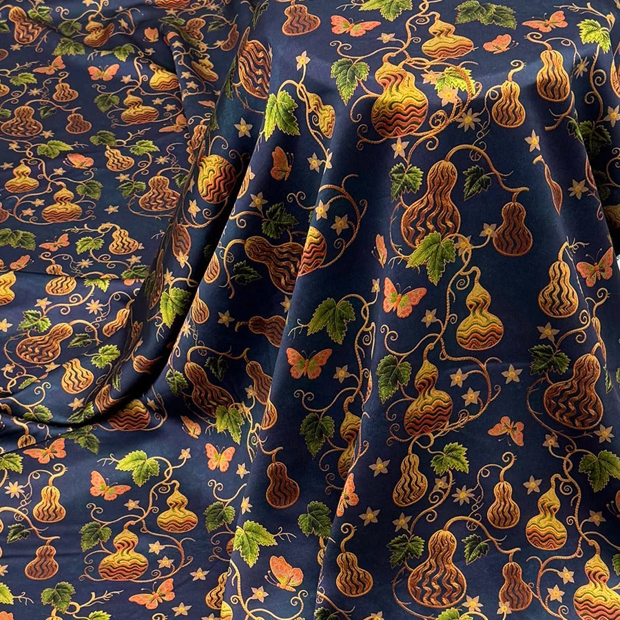 a fabric with a repeating pattern of gourds, butterflies, and leaves in shades of blue, green, and orange. The pattern is intricate and detailed, creating a visually striking and vibrant design.