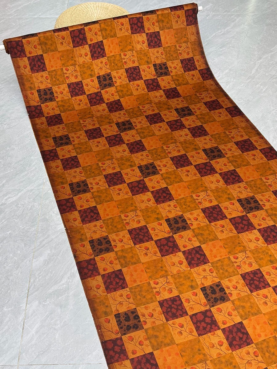 a roll of fabric with a vibrant, colorful pattern of squares and rectangles in shades of orange, brown, and black.