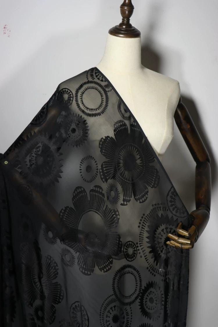 A mannequin wearing a black dress with a floral pattern on the front.