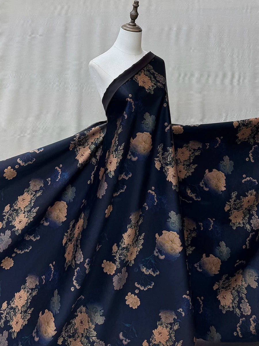 A mannequin wearing a long, flowing dress with a floral print in shades of blue and gold.