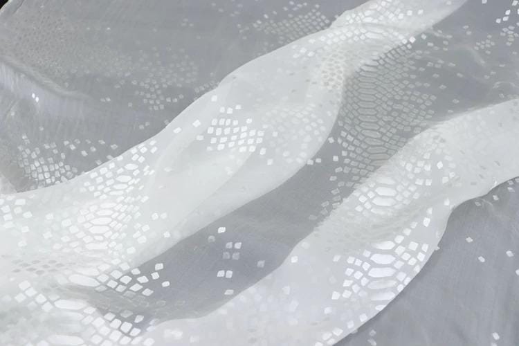 a close-up view of a white fabric with a pattern of small white squares or diamonds on it.