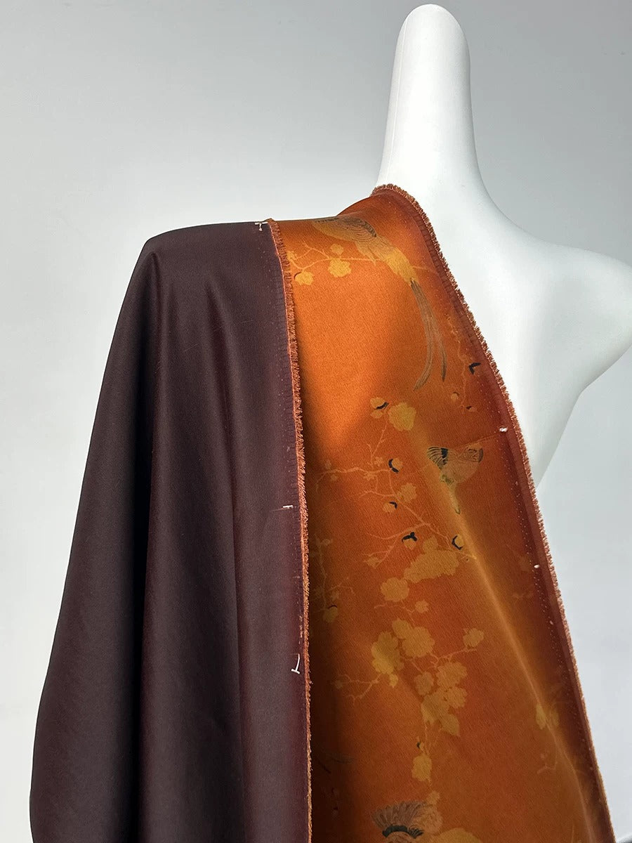 A mannequin wearing a brown and orange patterned fabric draped over its shoulder.