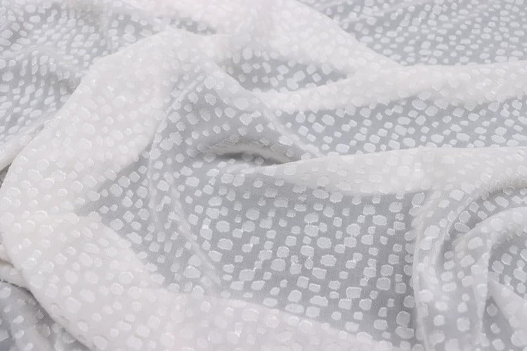 a close-up view of a white fabric with a pattern of small white dots or circles on it.