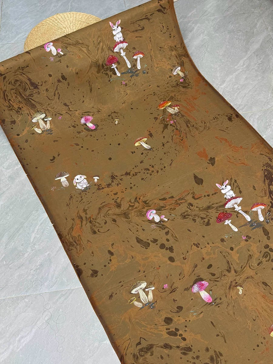 a brown fabric with a whimsical design of mushrooms and bunnies.