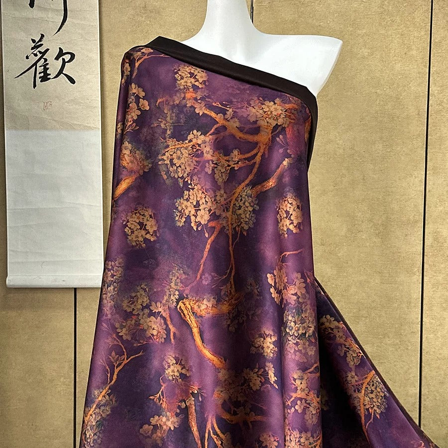 A mannequin wearing a purple and gold floral print dress with a black trim, displayed against a beige wall with a Chinese character sign.