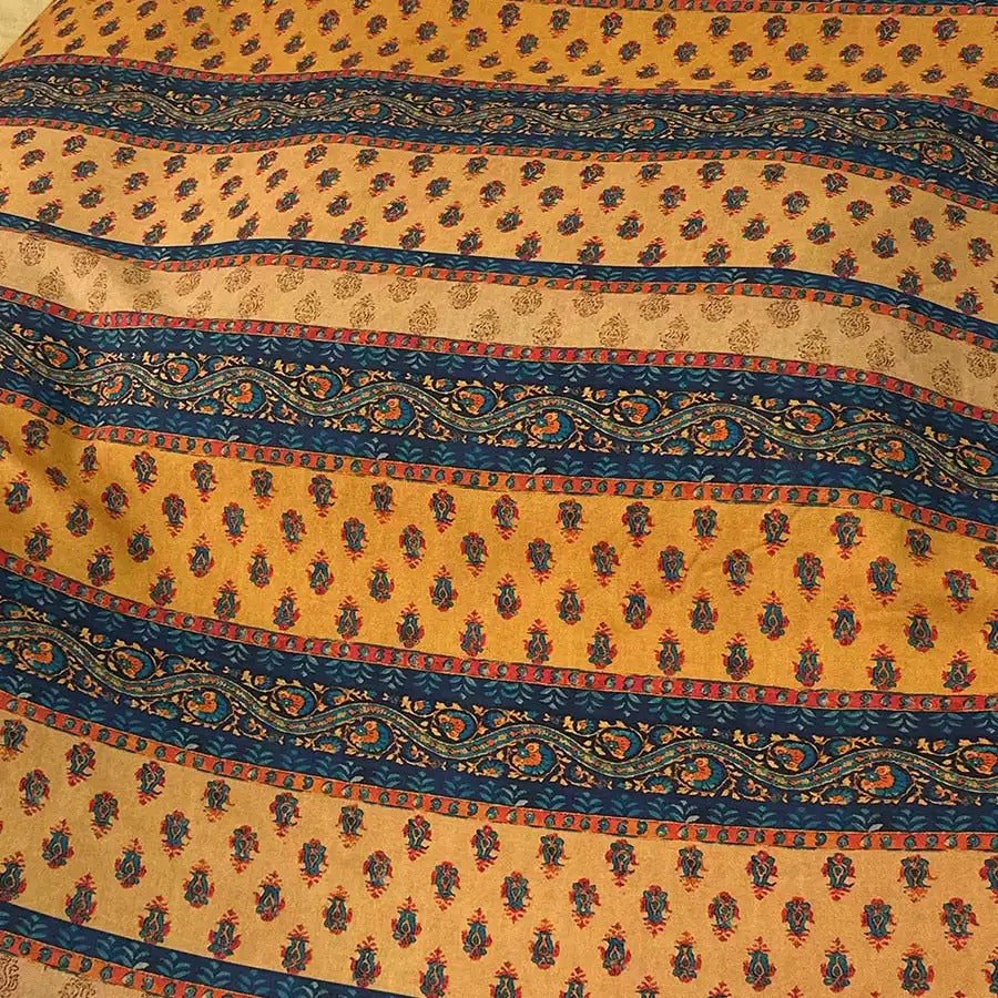 a close-up view of a fabric with a repeating pattern of yellow and blue stripes, along with a floral design. The pattern repeats across the fabric, creating a visually striking and intricate design.