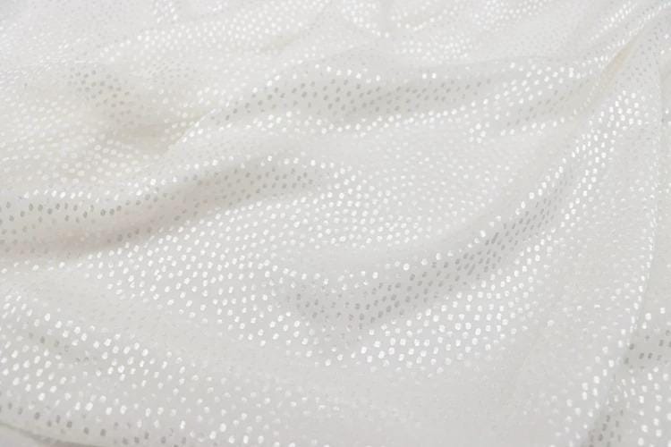 a close-up view of a white fabric with small white dots or sequins on it, creating a textured and shiny appearance.
