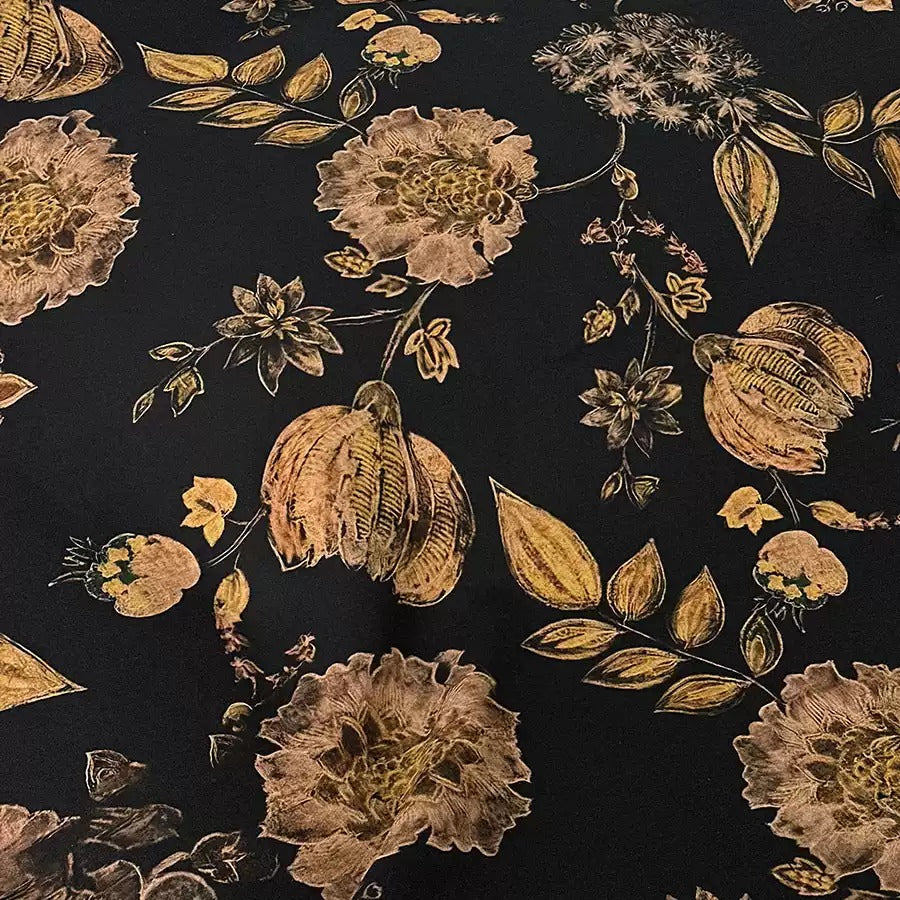 a close-up view of a black fabric adorned with a floral pattern in shades of gold and brown. The pattern includes various flowers, leaves, and other decorative elements, creating a visually striking and intricate design.