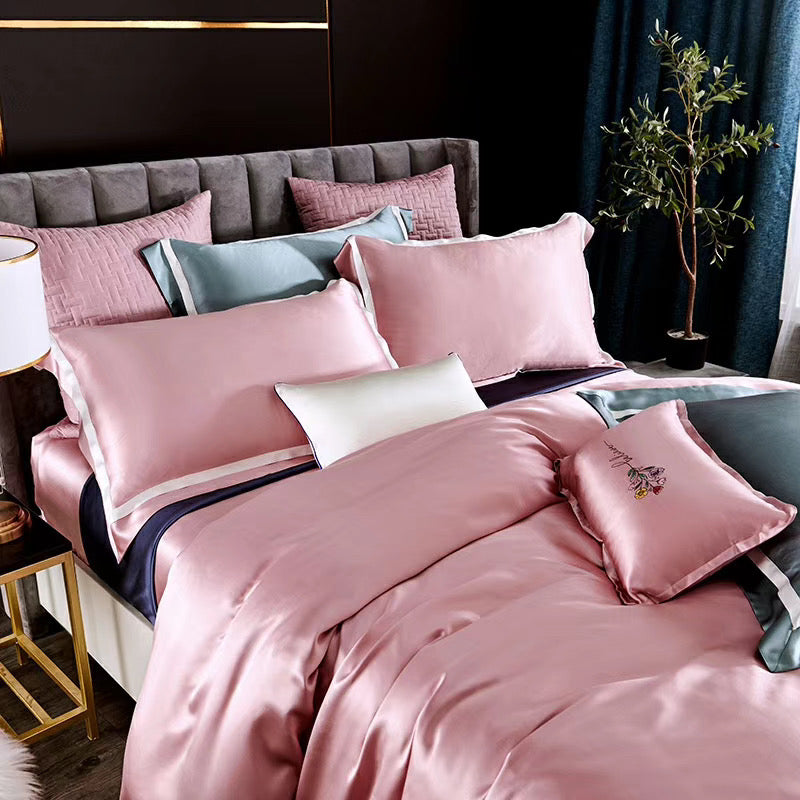 a bed with a pink comforter and pillows