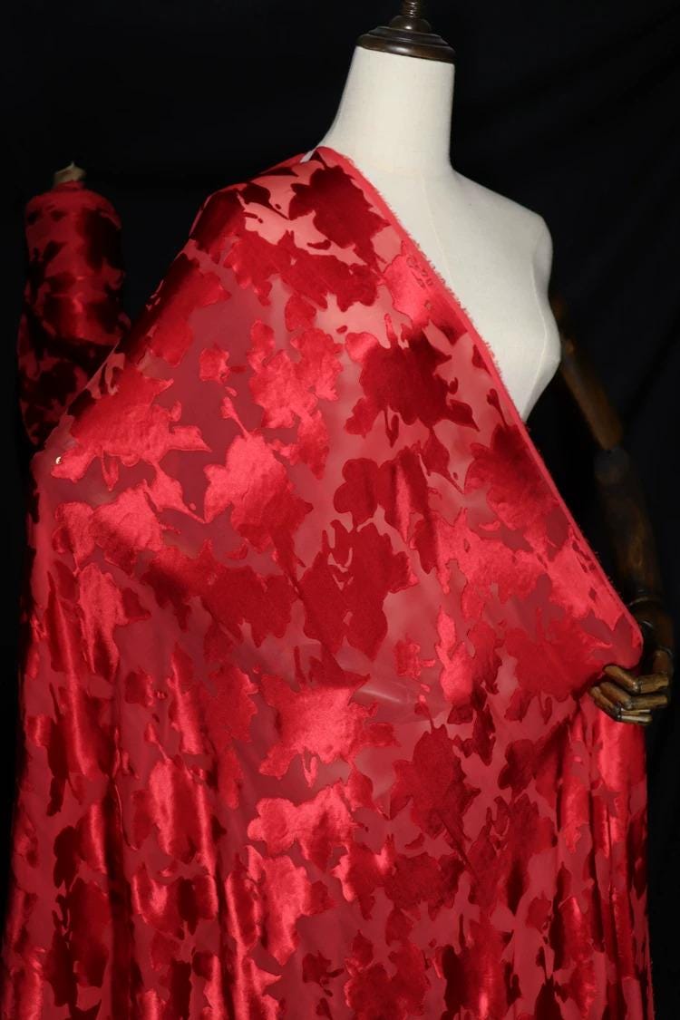 A mannequin wearing a red fabric with a floral pattern.
