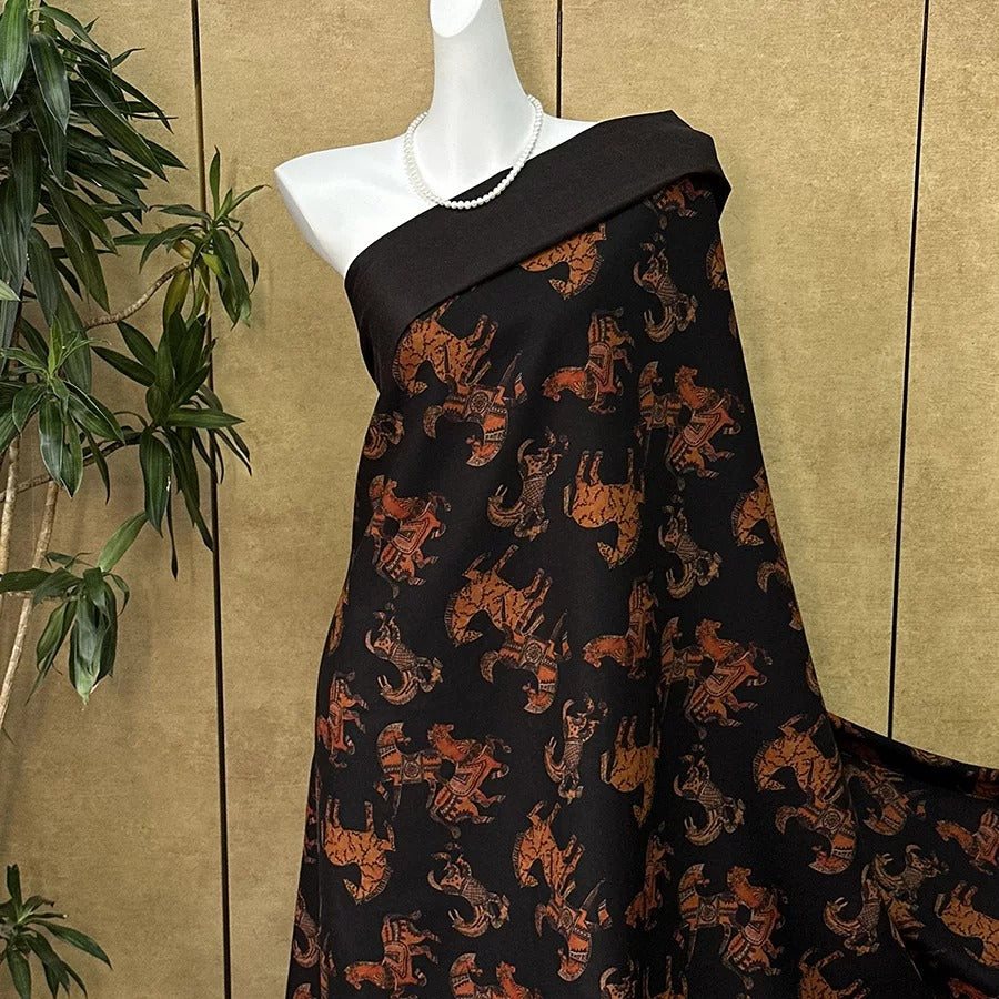 A mannequin wearing a black dress with a pattern of orange and brown animals, such as elephants and tigers, printed on it.