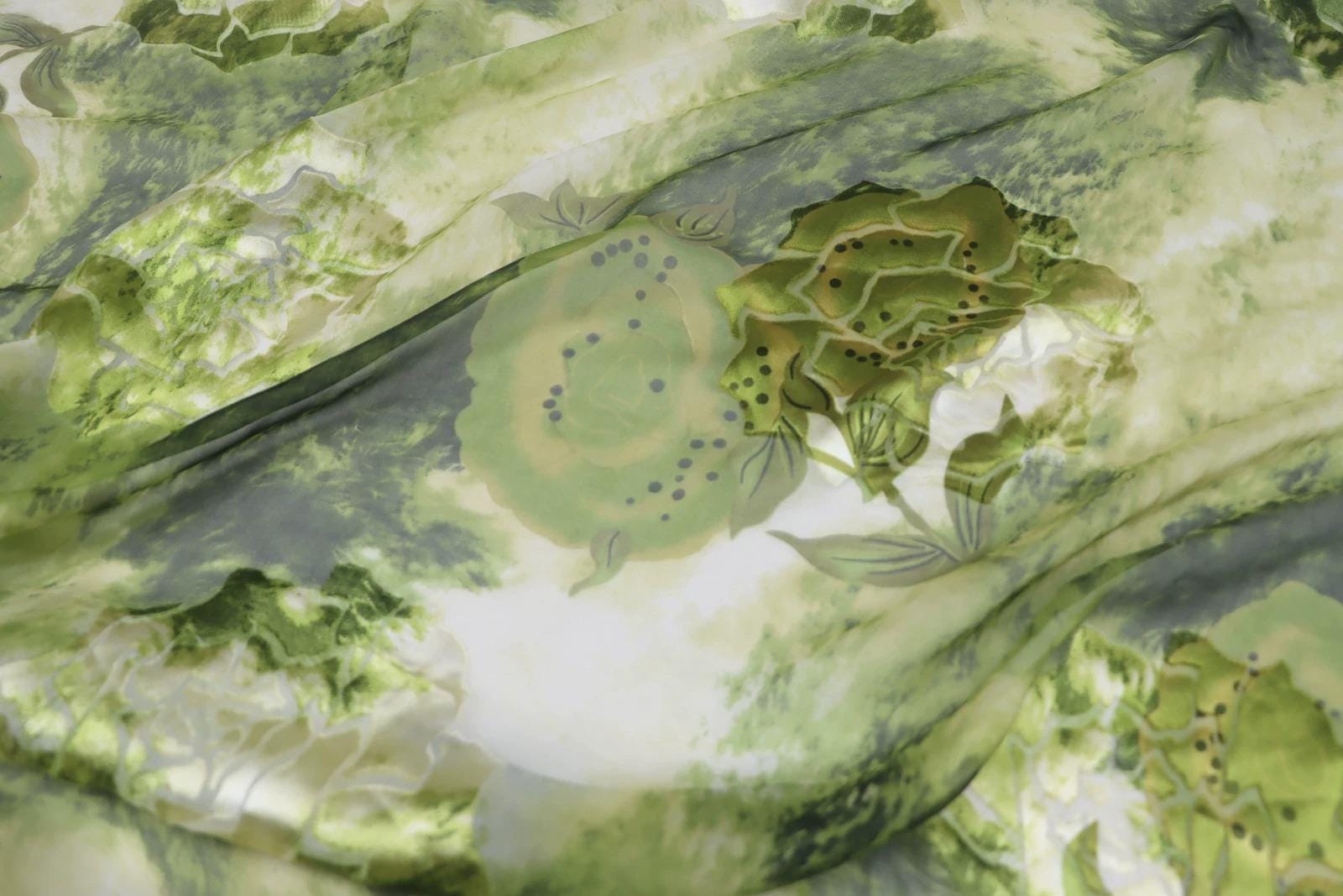 The image is a close-up of a fabric with a green and white floral pattern, featuring various shapes and textures.