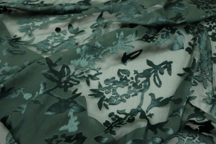 a close-up view of a fabric with a floral pattern, featuring a mix of green and black colors.