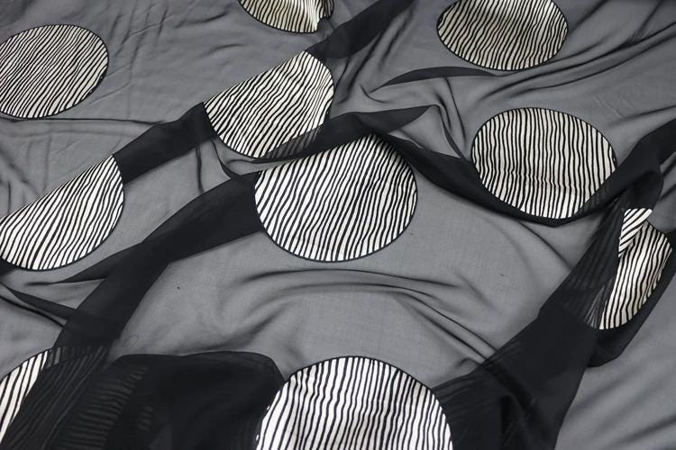 a close-up view of a fabric with a black and white striped pattern, including circular shapes.
