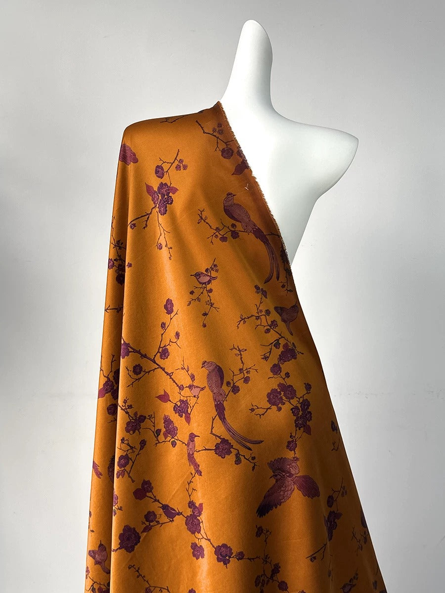 a mannequin wearing a vibrant orange fabric with a floral pattern. The fabric is draped over the mannequin, creating a visually striking display.