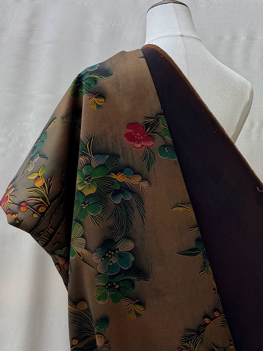 A mannequin wearing a brown fabric with a floral pattern, featuring a mix of green, red, and yellow flowers.