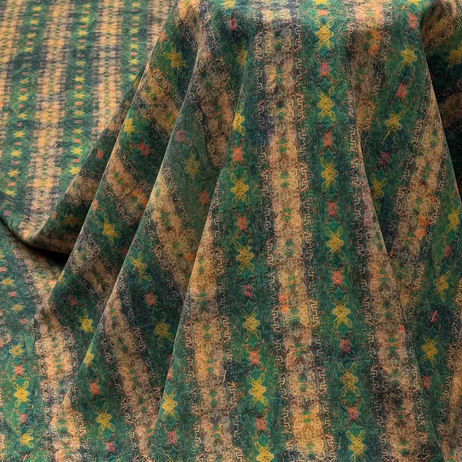 a close-up view of a fabric with a vibrant, colorful pattern featuring stripes and geometric shapes in shades of green, yellow, and orange.