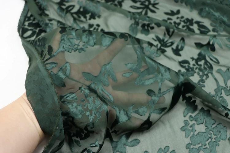 A close-up view of a hand holding a piece of fabric with a floral pattern.