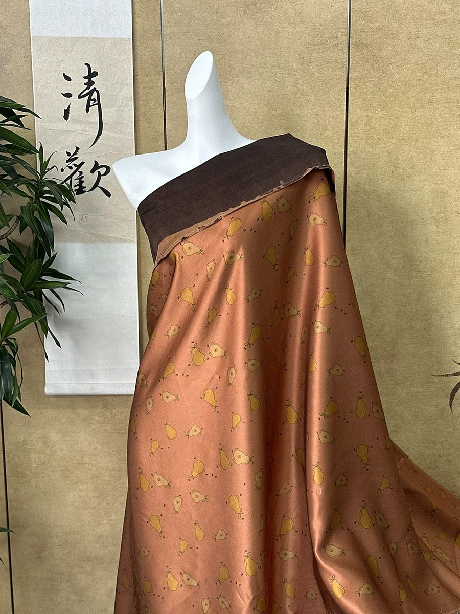 A mannequin wearing a brown and orange patterned dress with a pears pattern, displayed against a beige wall with a Chinese banner.