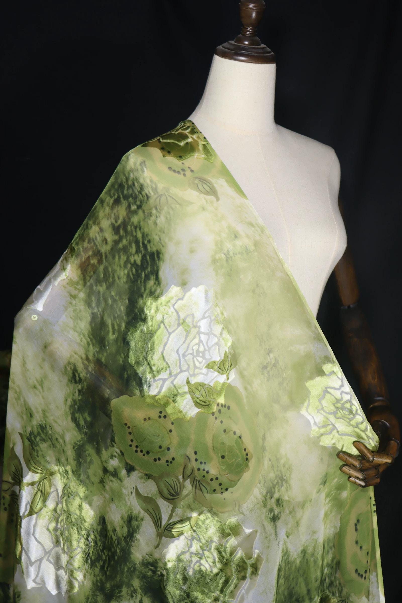 A mannequin wearing a green and white floral print fabric draped over its body.