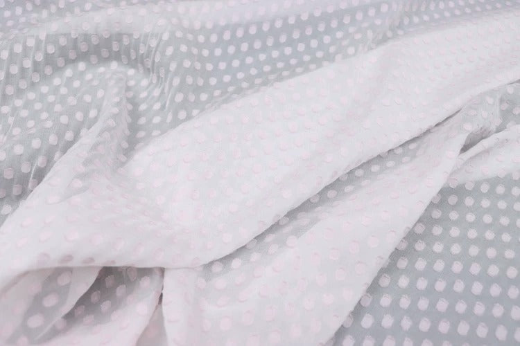 a close-up view of a fabric with a white polka dot pattern. The fabric appears to be a sheer material, with a light gray background. The pattern consists of small white dots arranged in a diagonal line across the fabric, creating a visually striking and textured appearance.