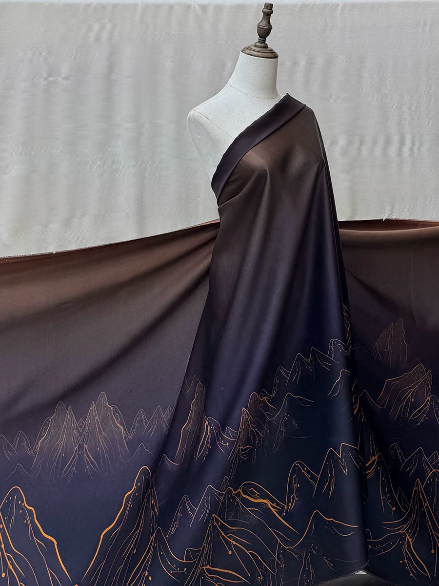 A mannequin wearing a long, dark-colored dress with a mountain landscape design printed on it.