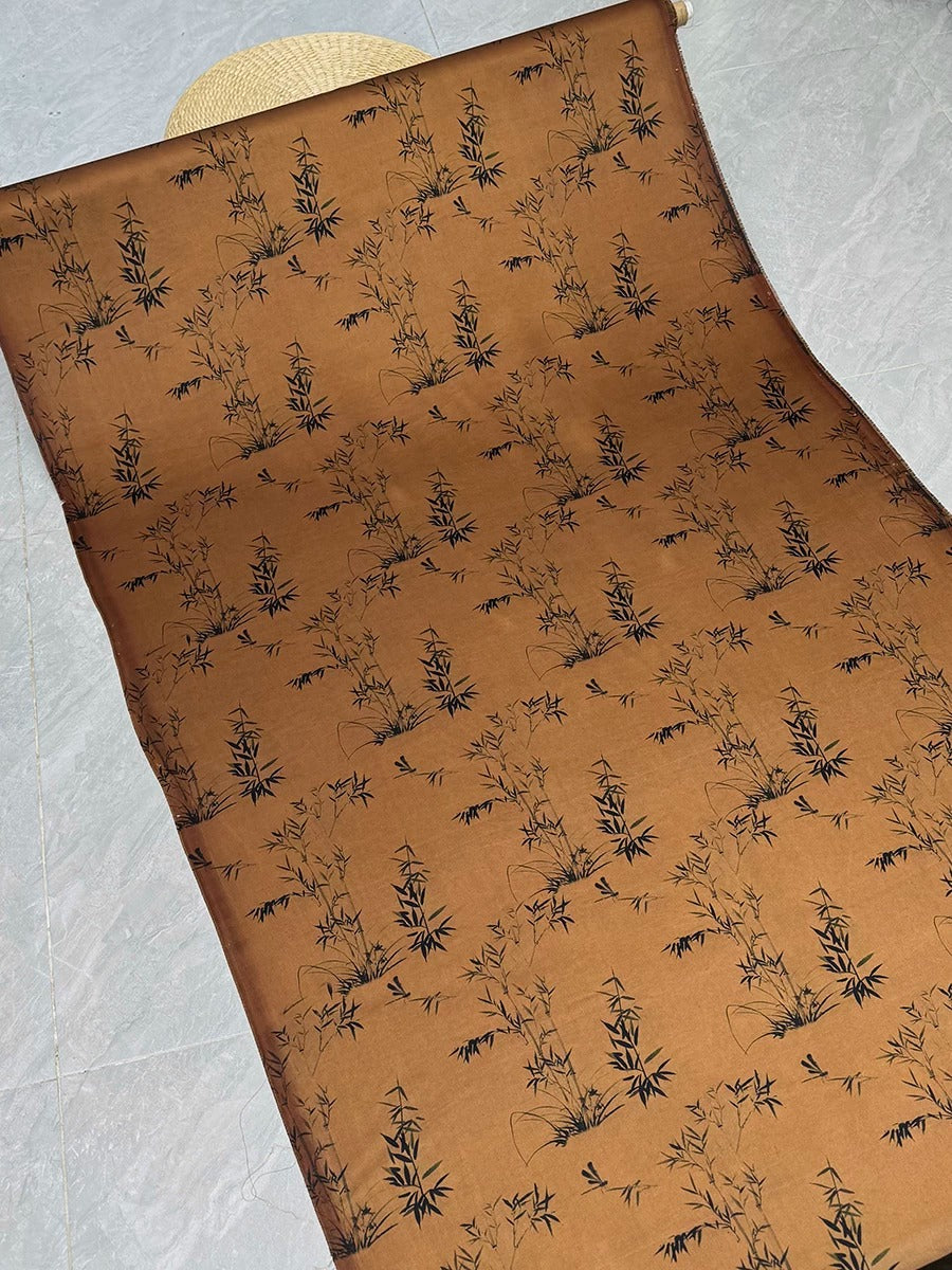 a brown fabric with a repeating pattern of black bamboo plants.