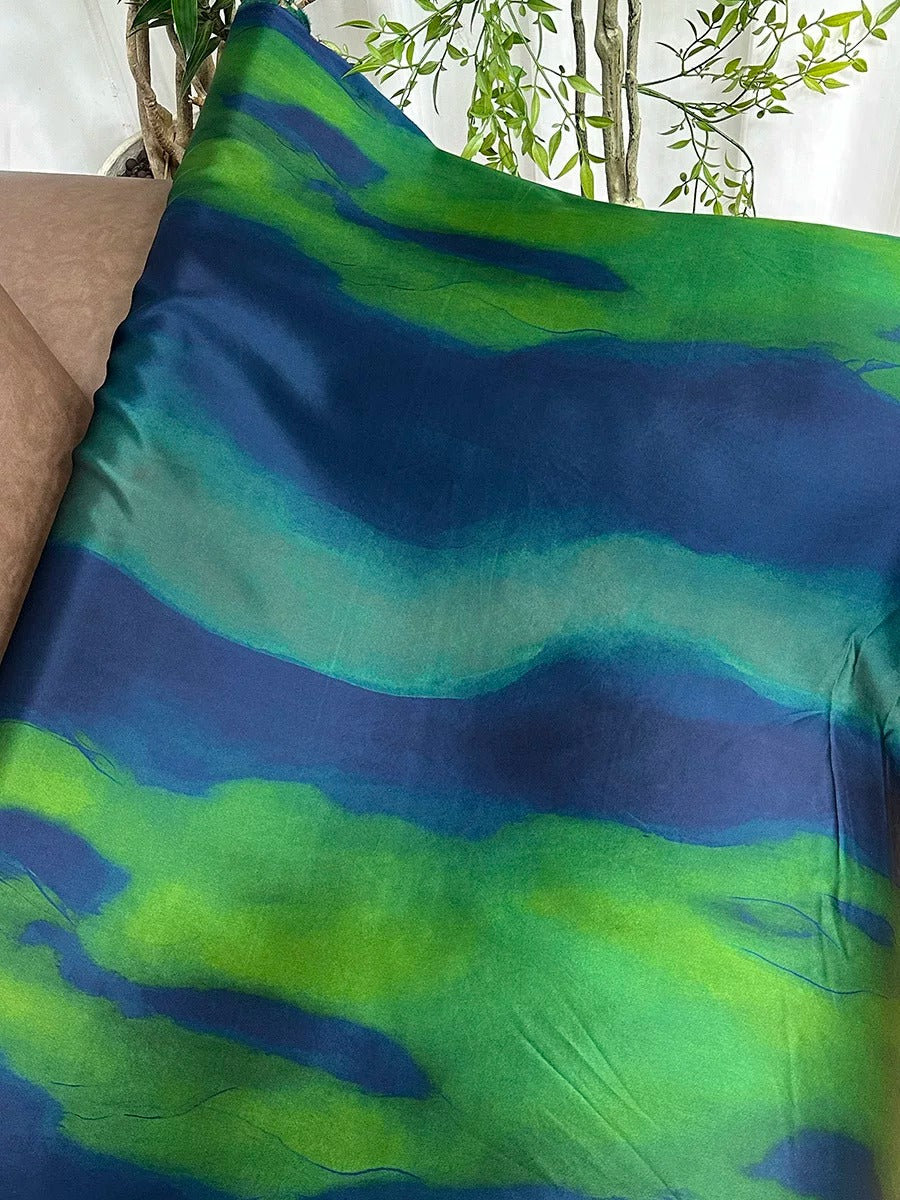 a vibrant, abstract fabric with a striking pattern of blue and green hues. The fabric appears to be a piece of clothing or textile, with the colors and design suggesting a sense of movement and energy.