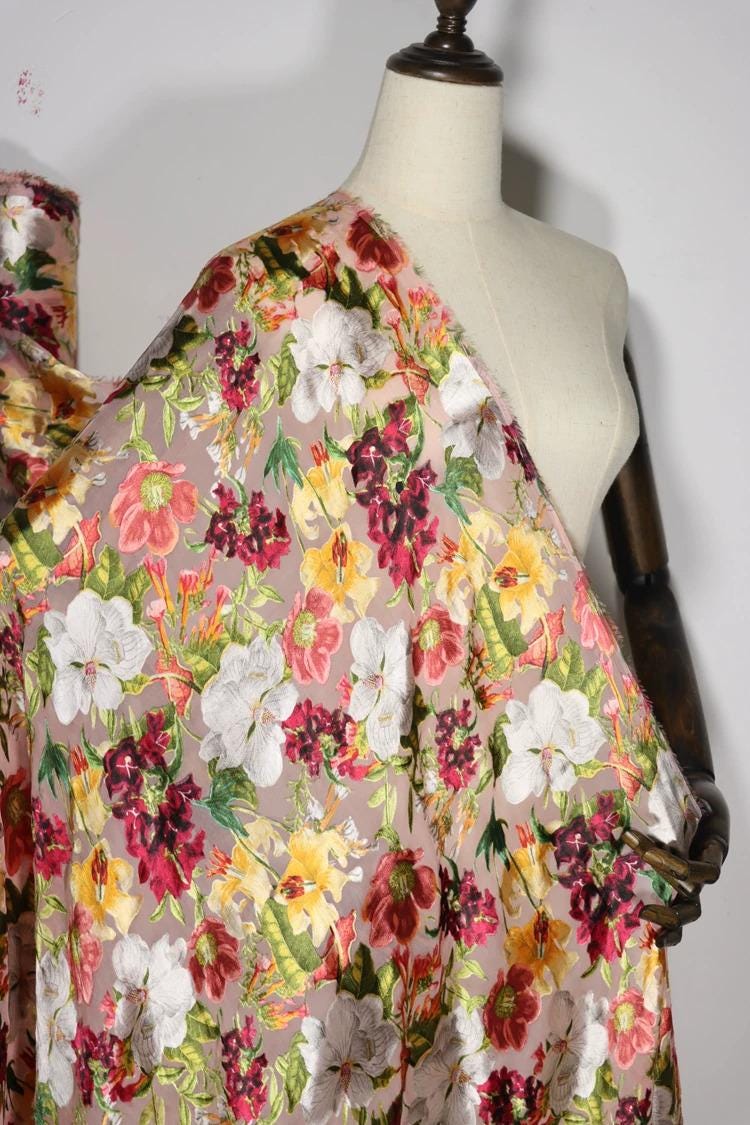 A mannequin wearing a white dress with a colorful floral print draped over it.