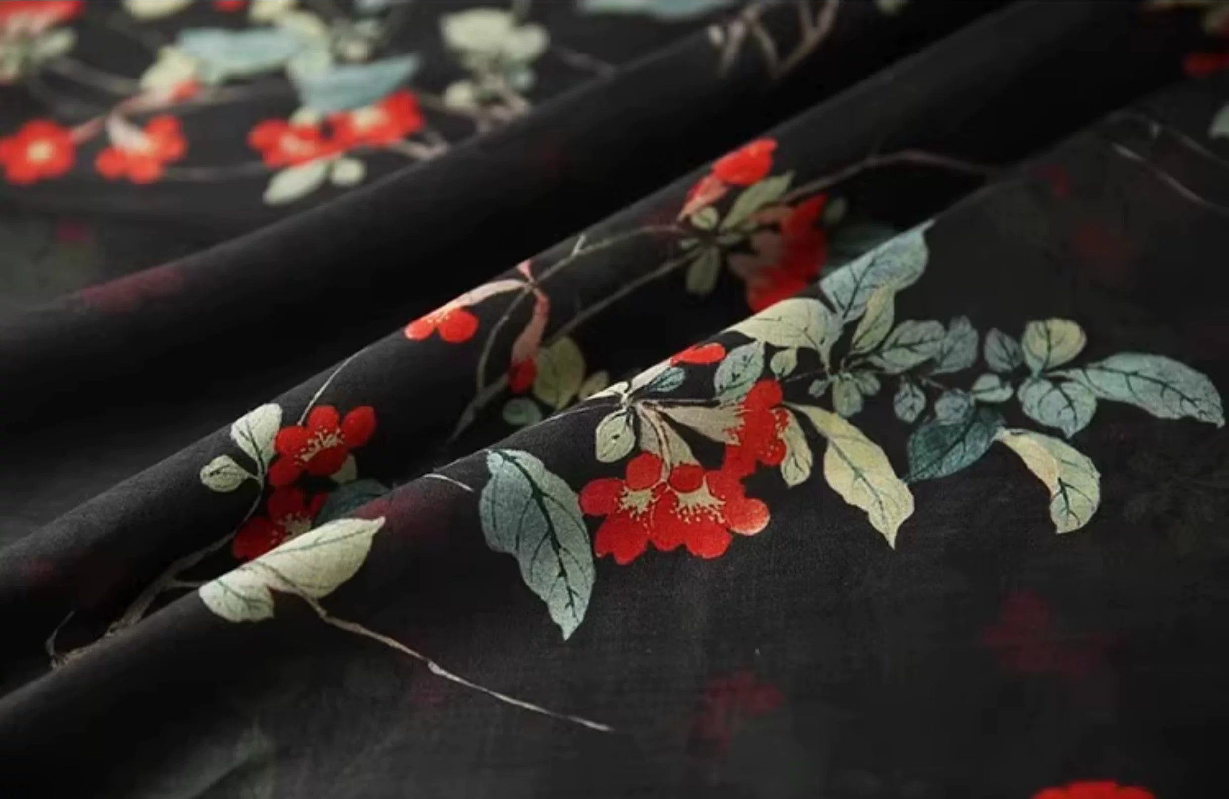a close-up view of a fabric with a floral pattern, featuring red flowers and green leaves.