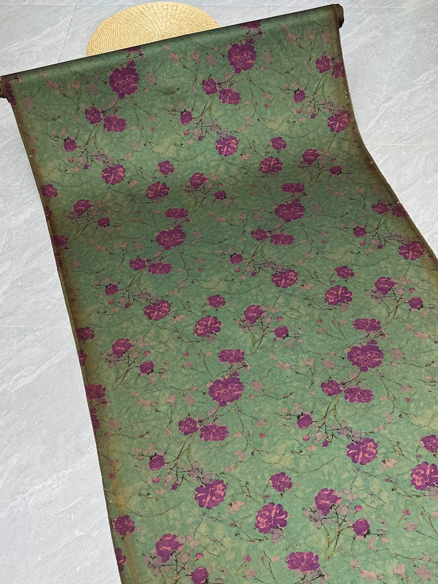 a roll of wallpaper with a floral pattern in shades of green and purple.