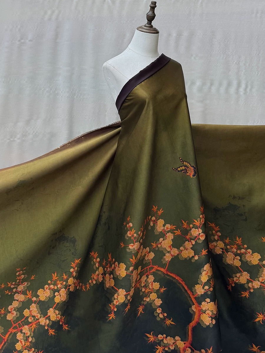 A mannequin wearing a long, flowing green dress with a floral pattern in shades of orange and yellow.