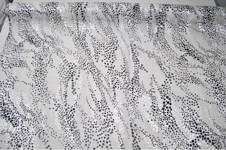 a close-up view of a fabric with a black and white polka dot pattern. The fabric appears to be a roll of material, possibly a piece of clothing or textile.