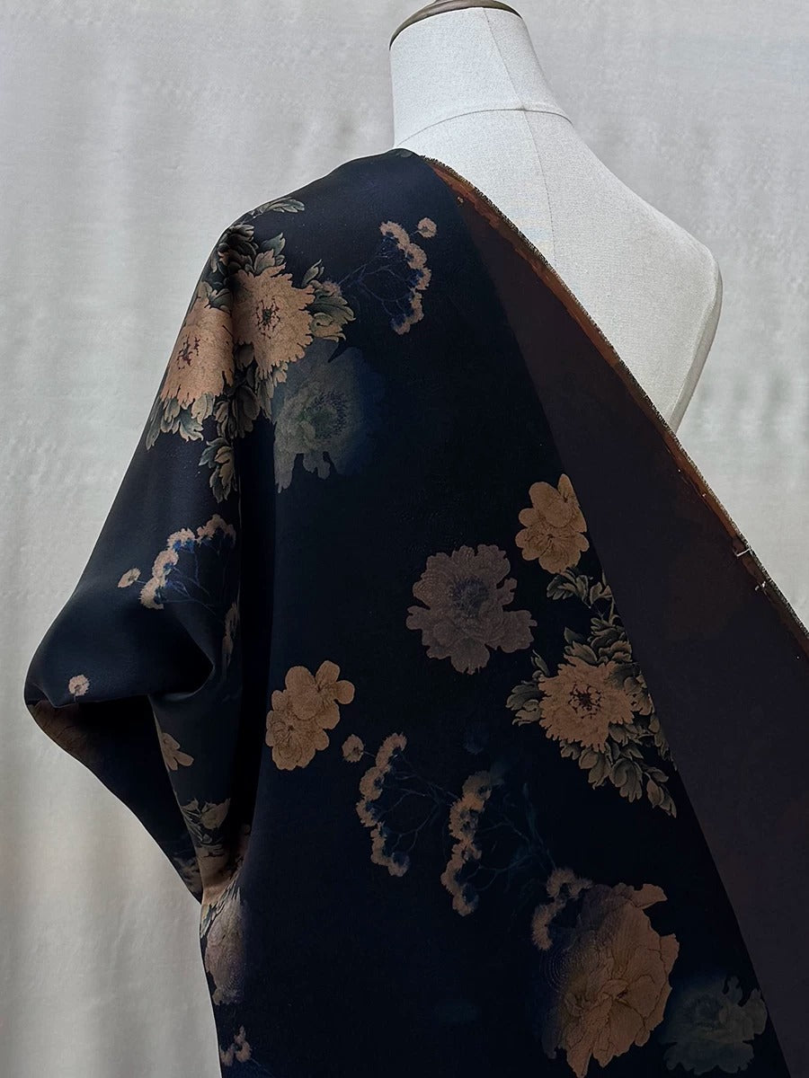 A mannequin wearing a dark blue fabric with a floral pattern, including pink and white flowers.