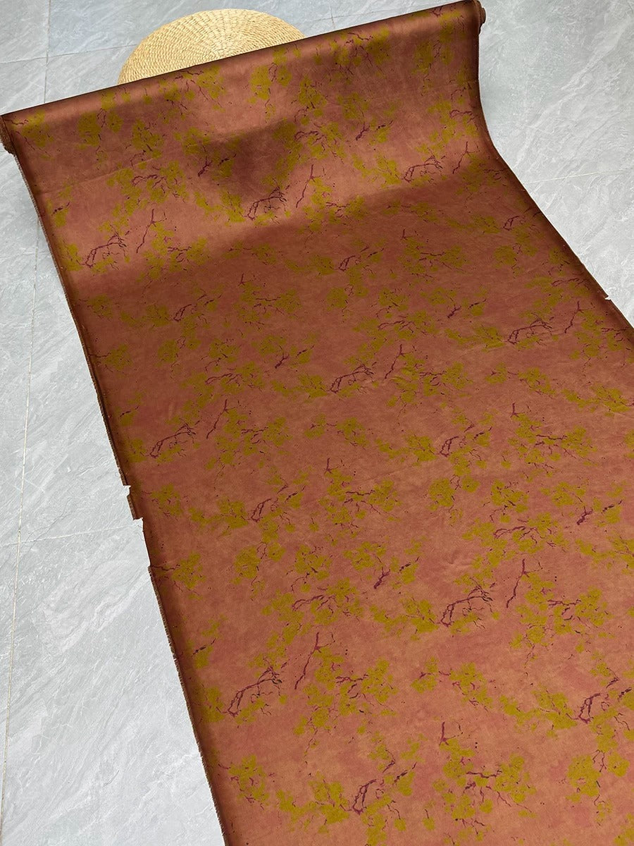 a roll of wallpaper with a floral pattern in shades of brown and green.